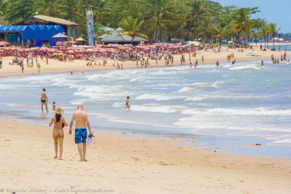 Imagem de um casal caminhando e admirando as belezas da Praia de Itacimirim.